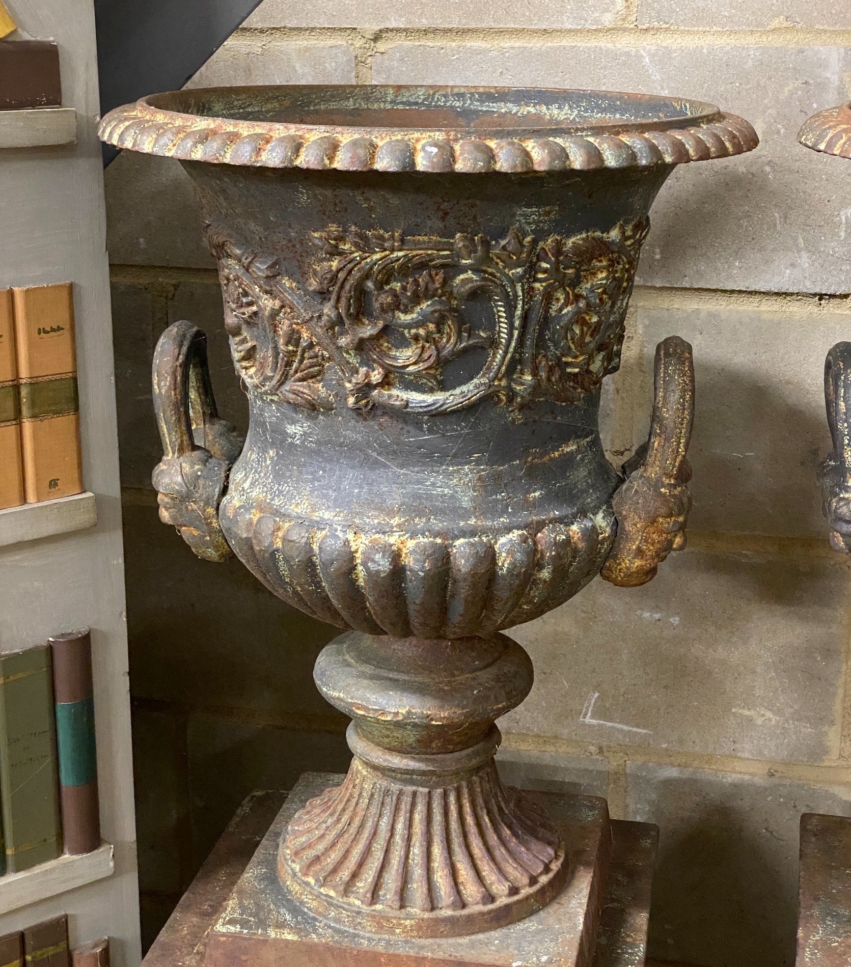 A pair of Victorian style cast iron campana garden urns on square plinths, height 110cm